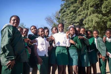 Real photo of happy black African kids in school uniforms, smiling and enjoying a break. A positive image of youth, education, diversity, and community spirit.の写真素材