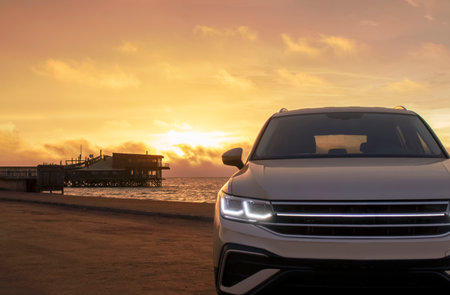 Gray Vehicle Near the Shoreline at Golden Hour â Exclusive Image Highlighting Adventure, Style, and the Tranquil Beauty of Driving Along the Coastline at Dusk.の写真素材