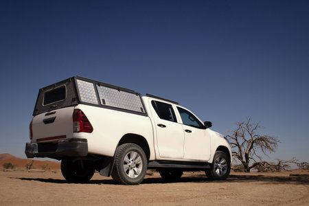 Powerful white SUV parked on sunlit desert sands, highlighting durability and the spirit of exploration. Ideal for themes of travel, off-road vehicles, and outdoor photography.の写真素材