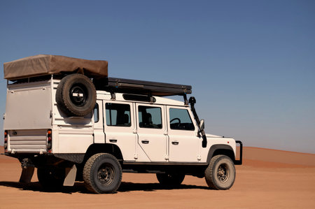 Powerful white SUV parked on sunlit desert sands, highlighting durability and the spirit of exploration. Ideal for themes of travel, off-road vehicles, and outdoor photography.の写真素材