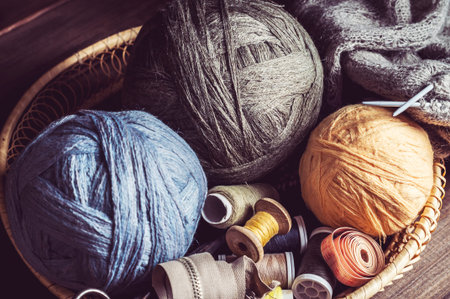 knitting, tangles scissors and coils in a basket on a wooden table