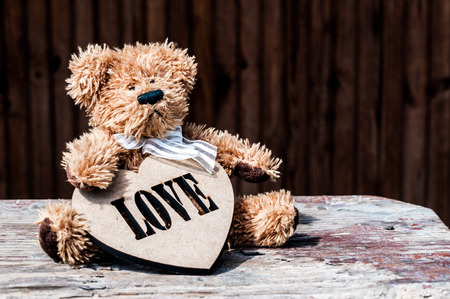 toy dog with a wooden heart on the tableの写真素材