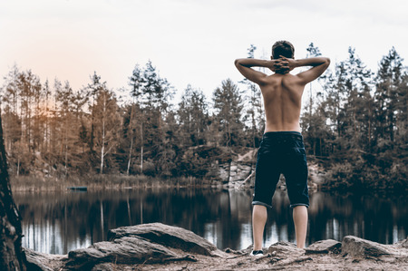 Teenager has a rest near the lake sits on a rockの写真素材