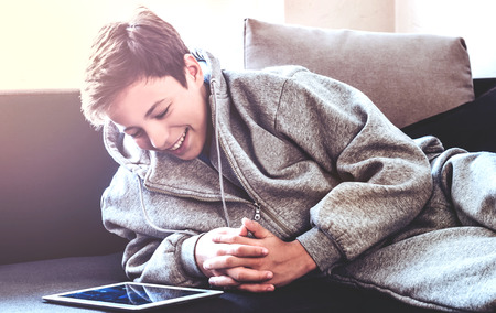 teenager with tablet while lying on the floor in the roomの写真素材