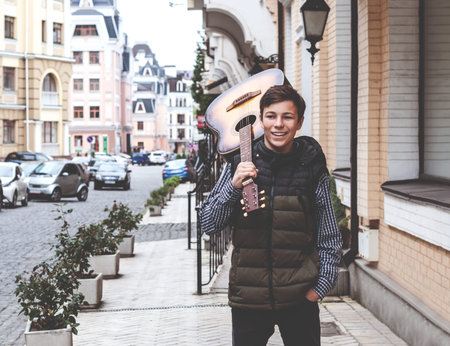 Young man with a guitar on a city street