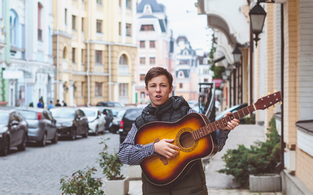 Young man with a guitar on a city streetの写真素材