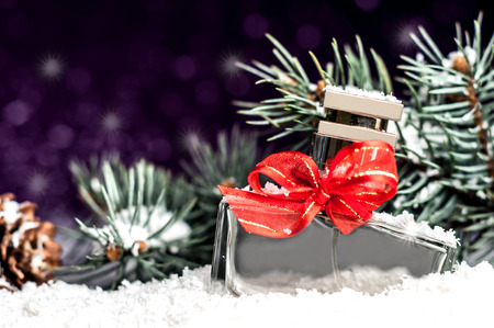perfume bottle with a red bow in snow on a purple backgroundの写真素材