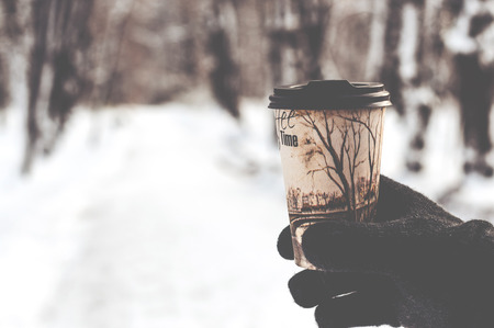 glass with hot coffee in male hand outdoors in winterの写真素材