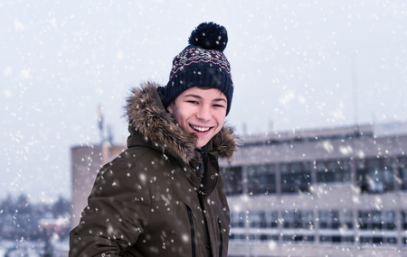 young man winter on a city street during a snowfallの写真素材