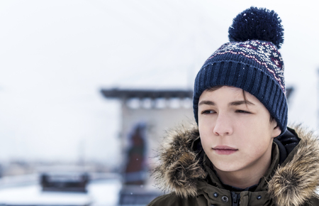 young man winter on a city street during a snowfallの写真素材