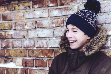 pensive teenager stands near of brick wallの写真素材