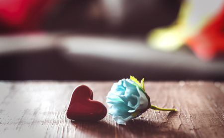 small red heart and blue rose on a wooden tableの写真素材