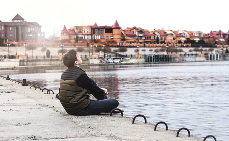 Stylish young man sitting near a Rivers on the waterfront の写真素材