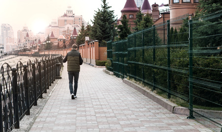 Stylish young man standing near a fence on the waterfrontの写真素材
