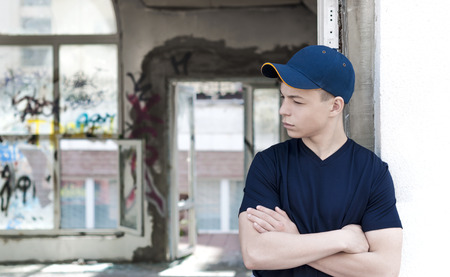 young man stands near an old broken windowの写真素材
