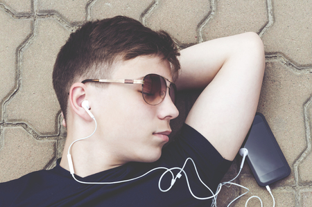 Stylish teenager in headphones listening to musicの写真素材