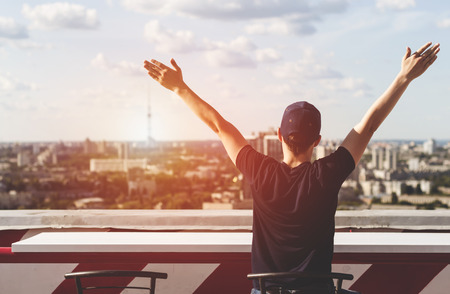 Young man looks at the city on the roof of a tall buildingの写真素材