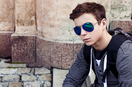 young man in glasses sits on the stairsの写真素材