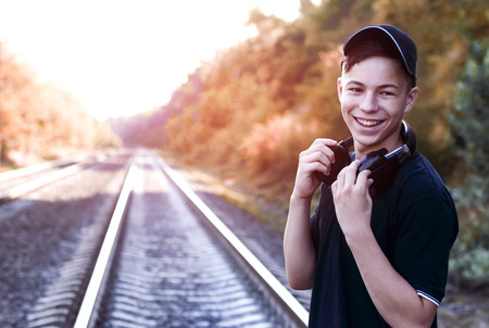 Modern young man with headphones listening to music on the railway tracksの写真素材