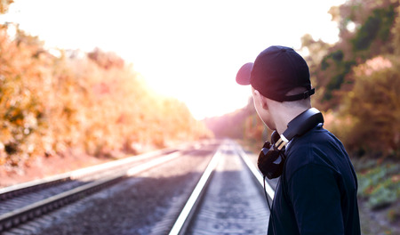Modern young man with headphones listening to music on the railway tracksの写真素材