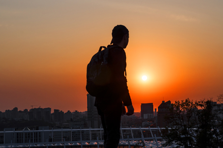 young man looks at a beautiful sunset in a big cityの写真素材