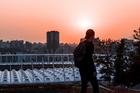 young man looks at a beautiful sunset in a big cityの写真素材