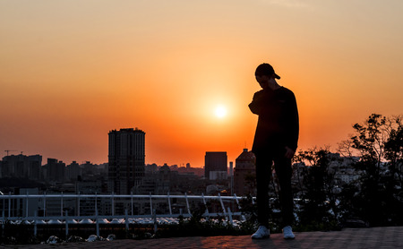 young man looks at a beautiful sunset in a big cityの写真素材