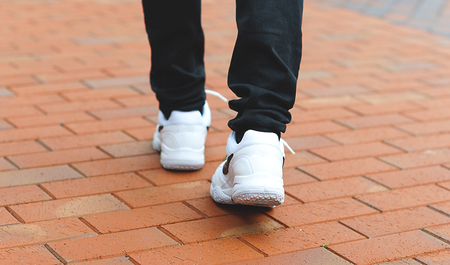 lower part of the male legs in white sneakers on the road made of bricksの写真素材