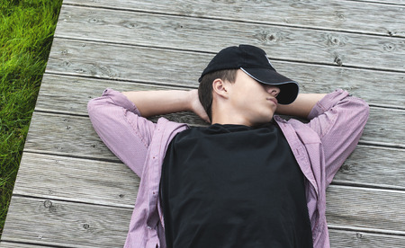 Young man lying down on wooden boardsの写真素材