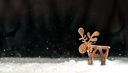 wooden Christmas toy, a deer, on a dark, snowy backgroundの写真素材