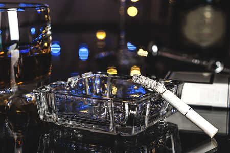 Smoldering cigarette in the ashtray on the table in the barの写真素材