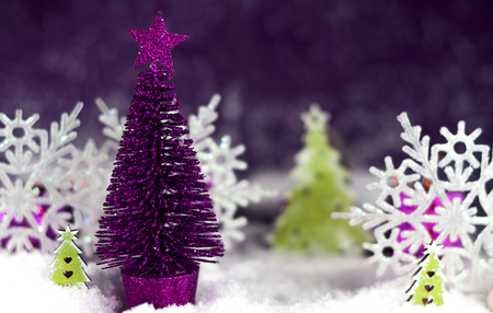 Vibrant purple Christmas tree with a star in the snowの写真素材