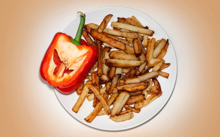 homemade fried potatoes on a plate, pepper on a yellow backgroundの写真素材