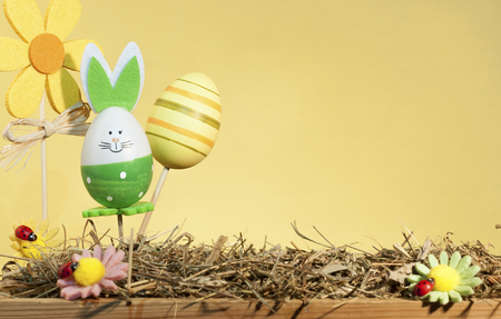 decorative easter decorations on a stick, on a yellow backgroundの写真素材