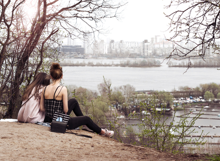 Two girls have a rest sitting on the slope of a high mountain in the afternoonの写真素材