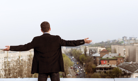 young man in a suit on the roof of a tall houseの写真素材