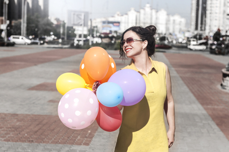 happy young woman with balloons on the city square on a summer dayの写真素材