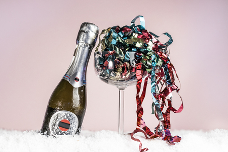 decorative bottle of champagne and a wineglass on a pink backgroundの写真素材