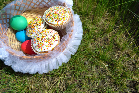 colored eggs and Easter cake in a basket on the grass