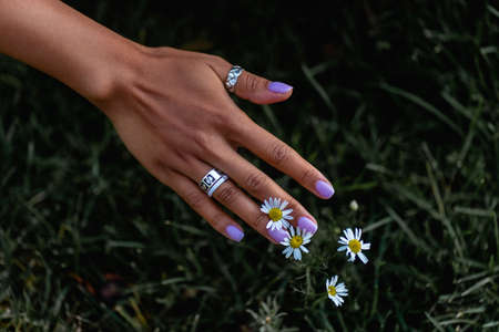 female hand with a beautiful manicure on a background of grassの写真素材
