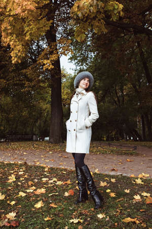 beautiful girl in a coat and a fur hat on an autumn landscapeの写真素材