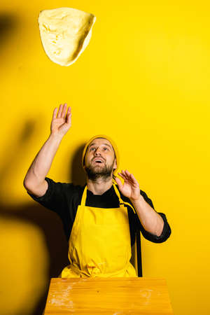 young attractive chef cook indian naan on yellow backgroundの写真素材