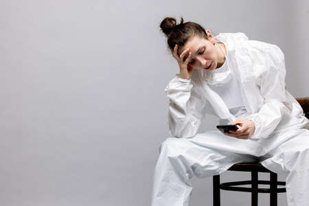 Tired doctor wearing mask and gloves at the hospital in coronavirus times, checking his smartphone.の写真素材