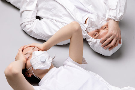 Two tired doctor male and female in a protective suit on the floor, exhausted in the fight against a...