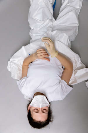 tired doctor female in a protective suit on the floor, exhausted in the fight against a pandemic covid-19の写真素材