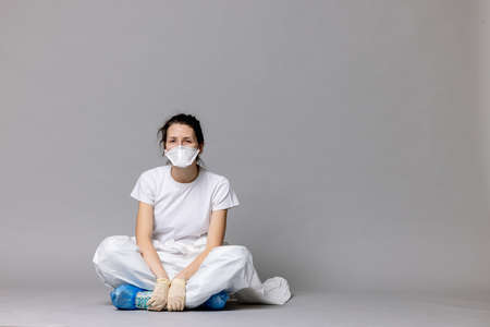 tired doctor female in a protective suit on the floor, exhausted in the fight against a pandemic covid-19の写真素材