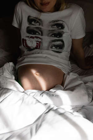 belly of a pregnant girl illuminated by the morning rays of the sunの写真素材