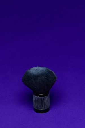 barber make-up brush with powder on violet background