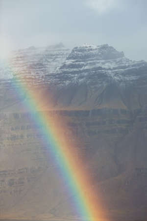Full rainbow over a mountain valley. Atmospheric alpine landscape with snowy mountains with rainbow in rainy and sunny weather.の写真素材