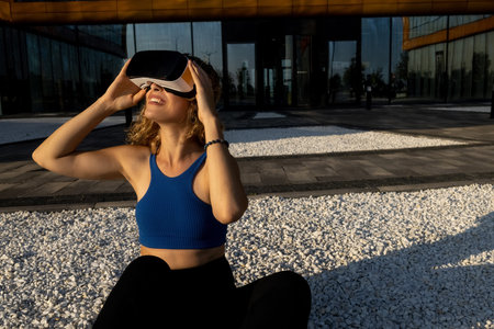 amazed young beautiful girl testing virtual reality 3D video glasses VR headset dressed in outfit...